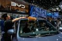 A worker wipes as visitors sit on a BYD Song Pro DM-i car model during the Auto China 2024 in Beijing (Andy Wong/AP)