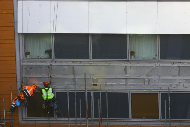 Workmen remove the cladding from the facade of a block of flats (Aaron Chown/PA)