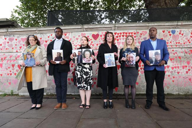 Bereaved people hold photos of loved ones lost to coronavirus (James Manning/PA)