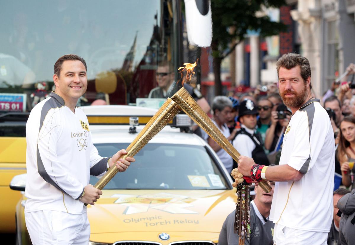 Torch Relay between Islington and The City of London: David Walliams passes the Olympic Flame to fundraiser Phil Packer, who suffered severe spinal injuries while on active service in Iraq...